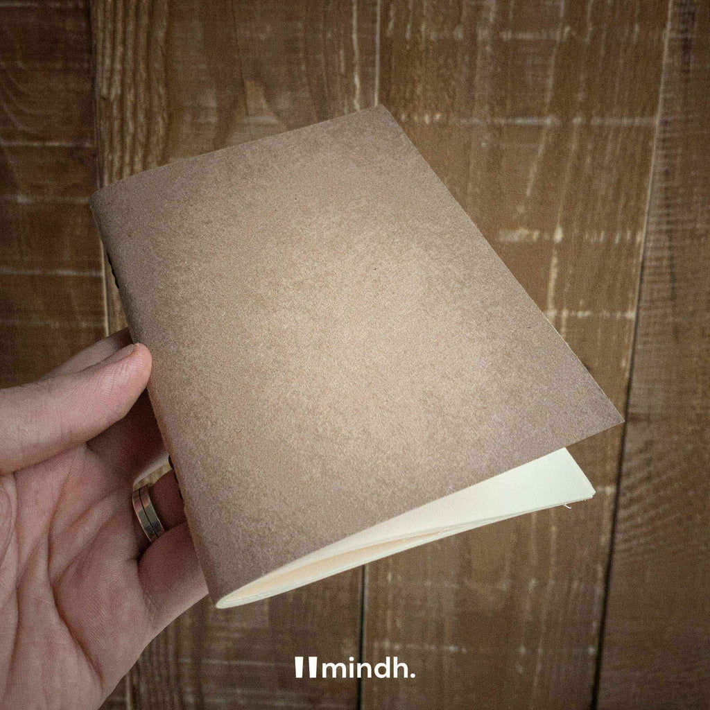 Hand holding a Traveler's Notebook with a kraft cover, showcasing its minimalist design and premium quality.